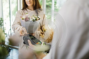 Close-up of unrecognizable male customer paying for her purchases with credit card in flower shop