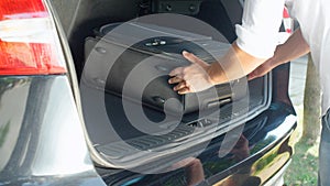 CLOSE UP: Unrecognizable man putting travel bags in the spacious car trunk.