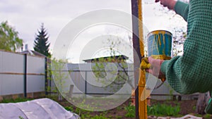 Close up of unrecognizable person paints metal pole with yellow paint on street. Concept of renovation and