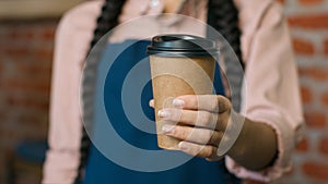 Close-up unrecognizable woman barista waitress in apron holding disposable paper cup with hot coffee or tea female small