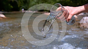 CLOSE UP: Unrecognizable woman pours water back into the river on sunny day.