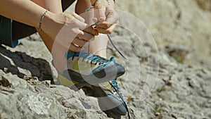 CLOSE UP: Unrecognizable woman ties her climbing shoes before climbing a boulder