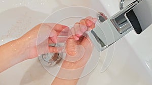 Close up of unrecognizable woman washing golden glitter of her hands into a washbasin at bathroom