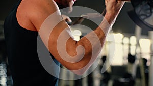 Close-up of unrecognizable young man with muscular wiry body lifting barbell.