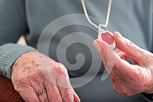 Close Up Of Unwell Senior Woman Holding Personal Alarm Button At