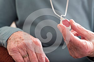 Close Up Of Unwell Senior Woman Holding Personal Alarm Button At photo