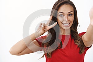 Close-up upbeat tender feminine young brunette woman, hold smartphone one hand, showing goodwill and wellbeing sign