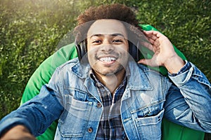 Close-up upper view shot of handsome african man with afro hairstyle extending hand towards camera while listening music