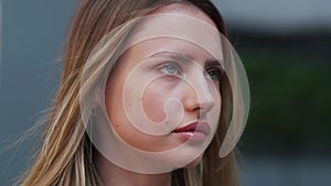 Close up upset female face of sad stressed caucasian girl woman standing outdoors not looking at camera with resentful