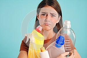 Close up upset girl holding empty plastic detergents in hands sadly looking in camera over colorful background isolated