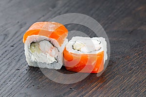 Close-up of uramaki sushi rolls with red caviar salmon tuna cucumber and avocado isolated on black background. Delicious