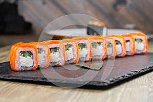 Close-up of uramaki sushi rolls with red caviar salmon tuna cucumber and avocado isolated on black background. Delicious