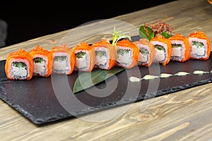 Close-up of uramaki sushi rolls with red caviar salmon tuna cucumber and avocado isolated on black background. Delicious