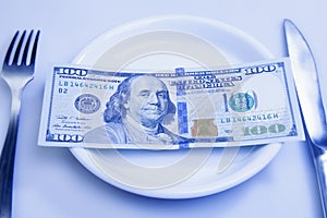 Close up of US Dollar on a plate, fork and knife as a symbol of