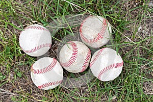 Close-up used baseballs on green grass field, sport concept