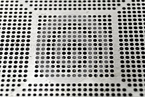 Close-up of used laser CNC high precision small pitch cut stencil for BGA chip reballing for electronics industry in partial focus