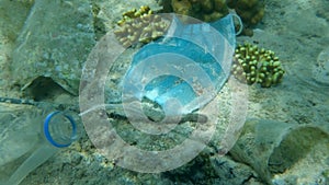 Close-up of used medical face mask and plastic garbage lies on seabed. Plastic and other garbage environmental pollution is proble