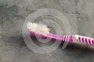 Close up Used pink toothbrush with cement background.