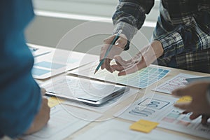 Close up ux developer and ui designer brainstorming about mobile app interface wireframe design on table with customer breif and