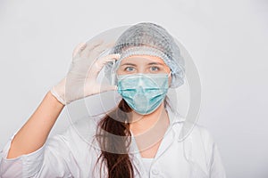 Close-up of a vaccine ampoule in the hands of a woman doctor. Lab technician in a white coat, medical hat, mask and gloves, holds