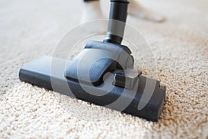 Close up of vacuum cleaner cleaning carpet at home