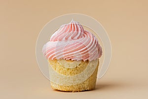 Close-up of vanilla cupcake with pink whipped butter cream top. Cream cheese frosting on muffin decorated with little pink heart