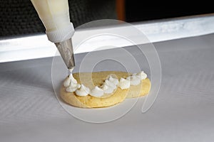 Close up of vanilla frosting being piped onto a heart shaped sugar cookie photo