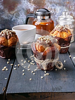 Close-up vanilla muffin with milk chocolate and nuts, flavored tea with orange on wooden background