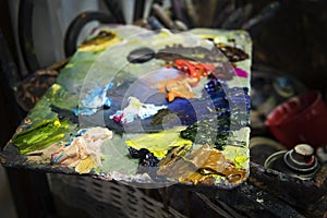 A close up of a varicoloured oil pallette in a painter workroom. An artist's palette consisting of diffrent oil paints. Oils spre