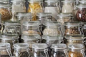 Close up of variety of dry foods, grains, nuts, cereals in glass jars.