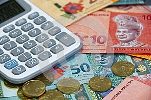 Close up of various Malaysia Ringgit currency and coins with calculator.