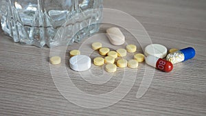 Close-up of various pills and a glass of water on the table