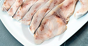 Close-up of various slices of raw swordfish, in a white plate, on a slate table..Tasty food from Italian cuisine and from the