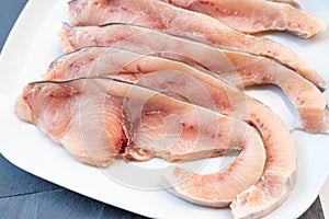 Close-up of various slices of raw swordfish, in a white plate, on a slate table..Tasty food from Italian cuisine and from the