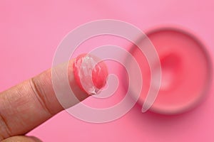 Close up of Vaseline on women finger on pink background