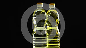 Close-up, vegetable refined and unrefined sunflower or corn oil in plastic bottles, food products rotate on black