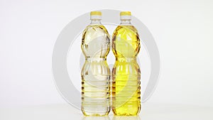 Close-up, vegetable refined and unrefined sunflower or corn oil in plastic bottles, food products rotate on white