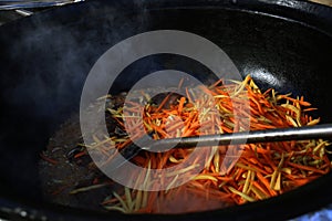 Close-up of vegetables cut into julienne strips and stewed in a pan