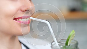 Close-up vegetarian female mouth drinking healthy cocktail holding straw by lips