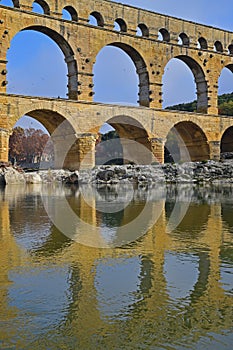 Close up vertical image of three arch level of Pont du Gard with clear reflection on Gardon River