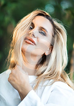 Close-up vertical portrait of beautiful blonde sexual 30 years old woman with make-up, wild hair and hand near face. Girl spring