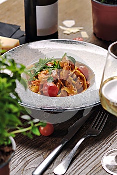 Close up vertical shot seafood pasta with sauce and cherry tomato served with white wine