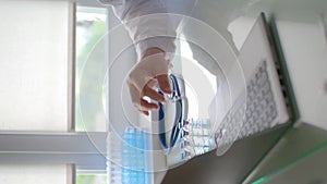 Close-up vertical video - a doctor places vaccine containers on a table near a laptop. He's going to write a report on