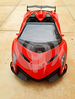 Close-up of a vibrant red toy sports car on a sleek floor