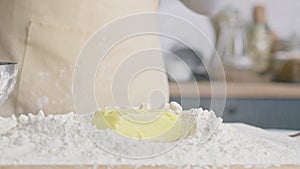 Close up video of falling block of butter into flour.