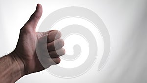 Close-up video of a left hand giving a thumbs up gesture against a white background