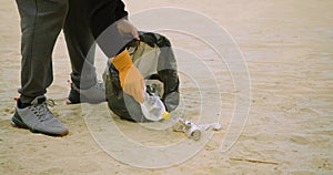 Close-up video of a man removing garbage on the beach.