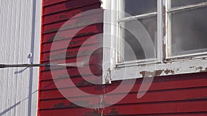 Close up video on Power washing loose paint with high pressure water blowing red color paint away from small wooden red house.