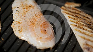 Close up video turning around seasoned hake fillet on a grill.
