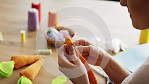 Close up video of woman sews handmade carrots.